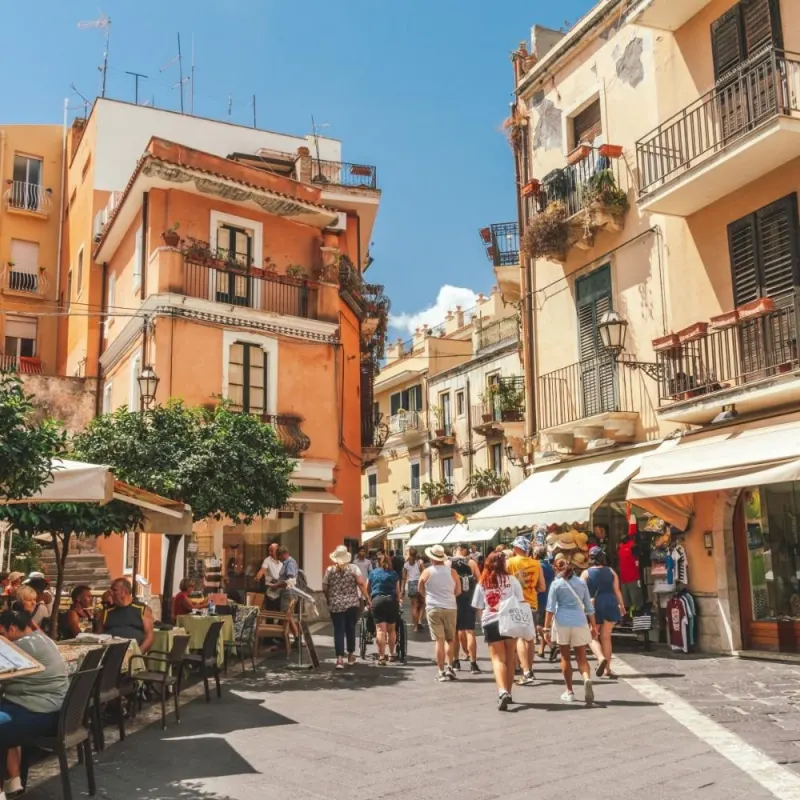 Busy pedestrian street with cafes and balconies in an Eastern Sicily town